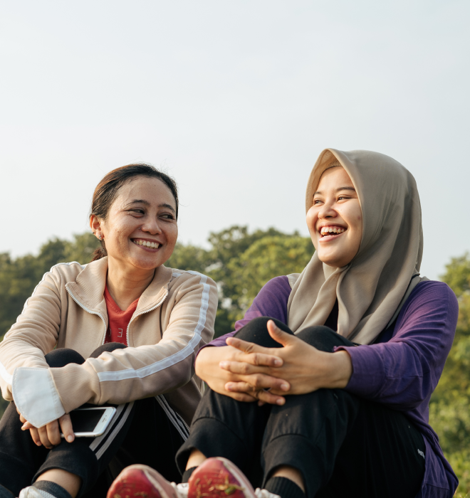 Two happy women converse outdoors.